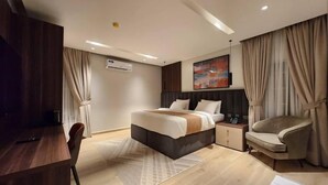 Una habitación de hotel moderna con una cama, un escritorio, una silla y una mesita de noche.