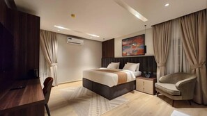 A modern hotel room with a bed, bedside tables, a desk, and a chair. - STAY AND HOMELY HOTEL (Abuja)