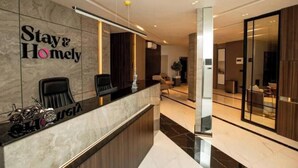 Zona de recepción con mostrador de mármol, un cartel que dice 'Stay & Homely' y una decoración con una motocicleta.