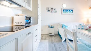 Ein kleines Zimmer mit einem Bett, einem Nachttischchen, einer Mikrowelle und einem Schrank.
