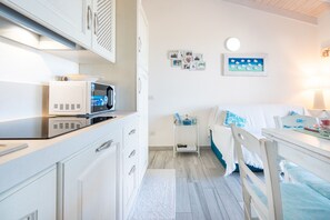 Ein kleines Zimmer mit einem Bett, einem Nachttischchen, einer Mikrowelle und einem Schrank.