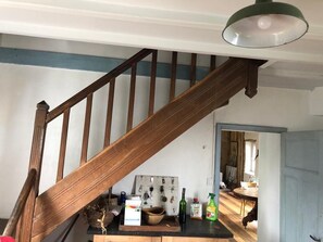 A wooden staircase with a light fixture above, a wall-mounted key rack, and a table with cleaning supplies. - Maison iris facing the sea (Étel)