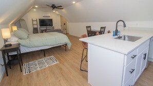 Un apartamento moderno y compacto con kitchenette, cama, comedor y ventilador de techo.