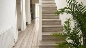 A staircase with a painting of a cityscape, a potted plant, and a white interior. - 4Bed House with parking and GYM /London/Edgware (Edgware)