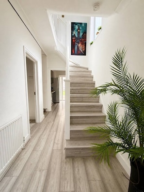 A staircase with a painting of a cityscape, a potted plant, and a white interior. - 4Bed House with parking and GYM /London/Edgware (Edgware)