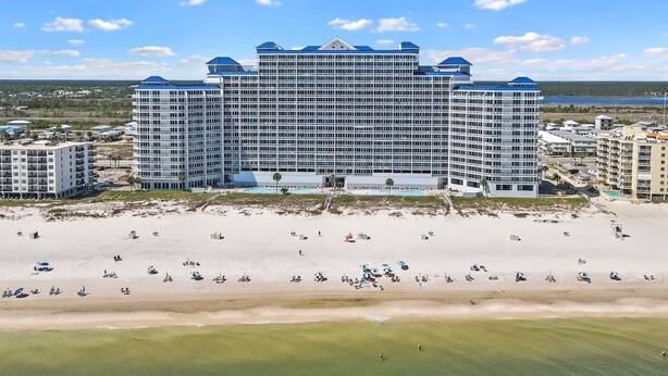 Ein großes Hotel mit mehreren Etagen und einem zentralen Innenhof, direkt am Strand gelegen und mit Blick auf das Meer.