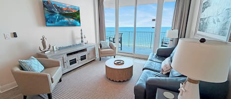 A modern living room with a large window, a ceiling fan, and a flat-screen TV.