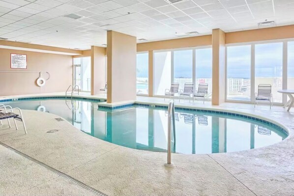 Une piscine intérieure offrant une vue dégagée sur la ville grâce à de grandes fenêtres.