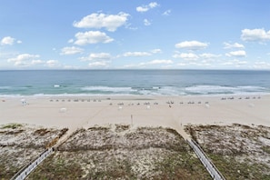 Ein Strand mit sandigem Ufer, einer Umzäunung und blauem Himmel.