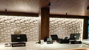A reception desk with a modern geometric wall design, a cash register, and a reception sign. - Hotel O Chil SEZ Coimbatore (Coimbatore)