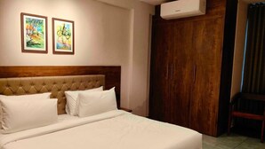 A hotel room with a large bed, a wooden headboard, two framed pictures on the wall, a wardrobe, and an air conditioning unit. - Hotel O Chil SEZ Coimbatore (Coimbatore)
