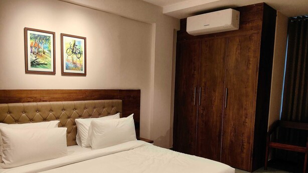 A neatly made bed with white linens, a wooden headboard, and two framed artworks on the wall. - Hotel O Chil SEZ Coimbatore (Coimbatore)