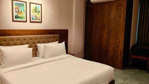 A bedroom with a tufted headboard, a large bed with white linens, and two framed artworks on the wall. - Hotel O Chil SEZ Coimbatore (Coimbatore)