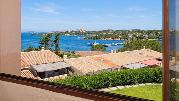 A coastal view with buildings, a clear sky, and boats in the water. - Holiday Home 'Vista Sul Blu - Costa Smeralda' with Sea View, Shared Pool and Wi-Fi (Cala Bitta)