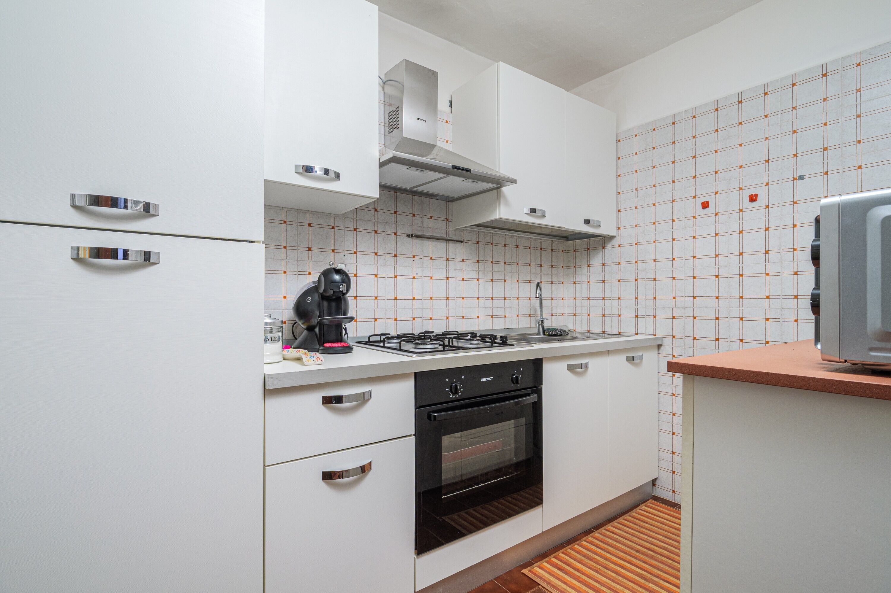 A modern kitchen with white cabinets, a gas stove, an oven, and a microwave.