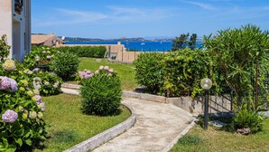 A garden pathway leading to a building with a view of the sea. - Holiday Home 'Vista Sul Blu - Costa Smeralda' with Sea View, Shared Pool and Wi-Fi (Cala Bitta)