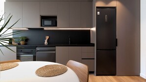 Une cuisine moderne équipée d’un four à micro-ondes encastré, d’un réfrigérateur et d’un coin repas avec une table et des chaises.