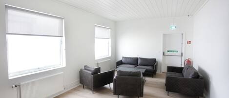 Una habitación de hotel moderna con un ventanal grande, un conjunto de sofás y un radiador.