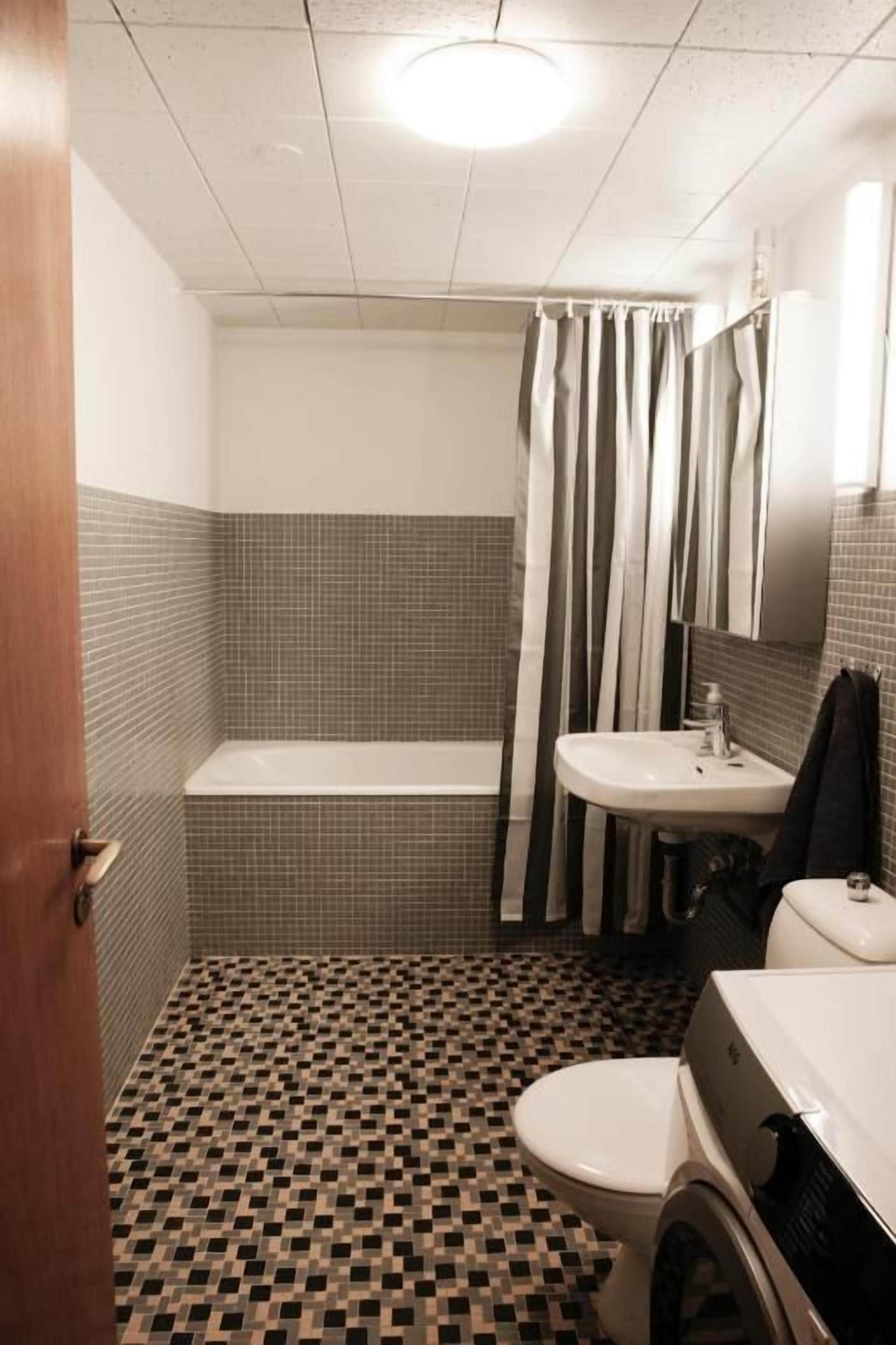 Un baño con suelo de baldosas, una bañera, un inodoro y un lavabo.