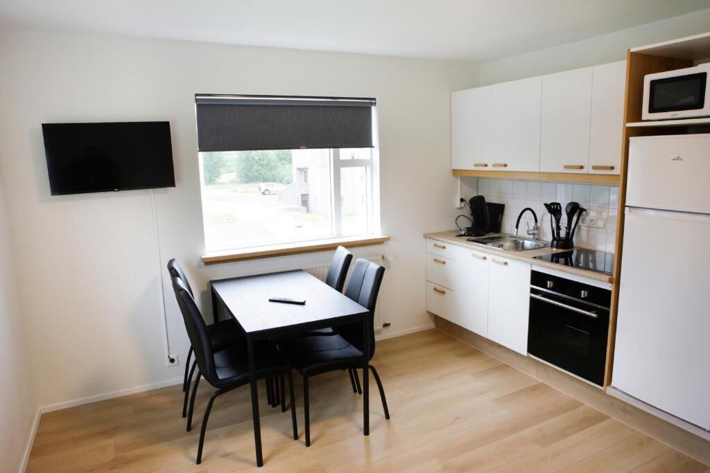 Una cocina compacta con mesa, sillas, televisor y ventana.