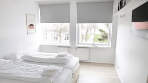 A bedroom with a bed, two windows, and a radiator. - Eiðar Hostel and Apartments (Eiðar)