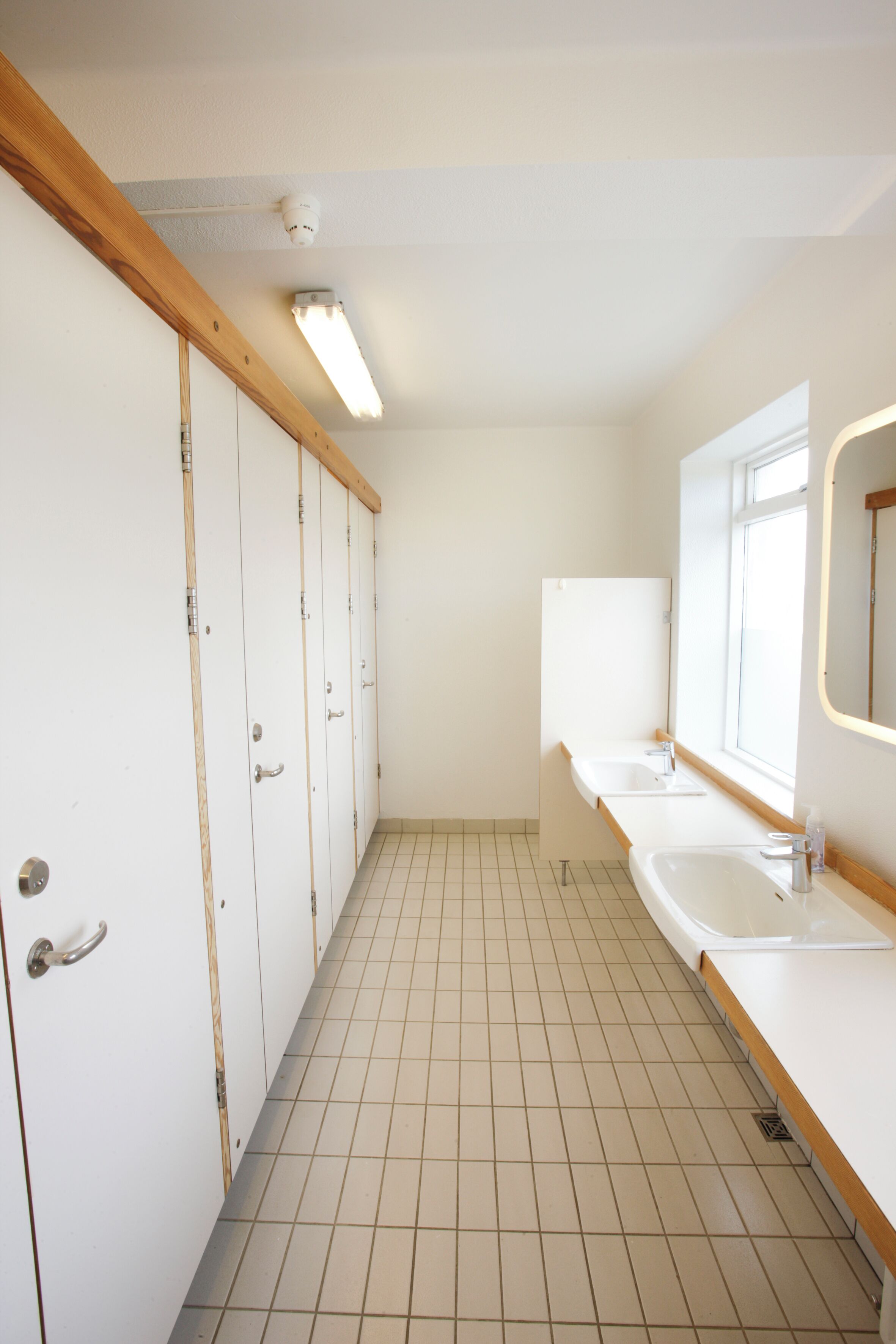 A clean, modern bathroom with white lockers, a sink, and a mirror.