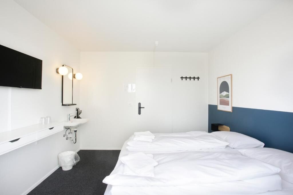 A hotel room with a bed, a sink, a toilet, a door, and a framed picture on the wall.