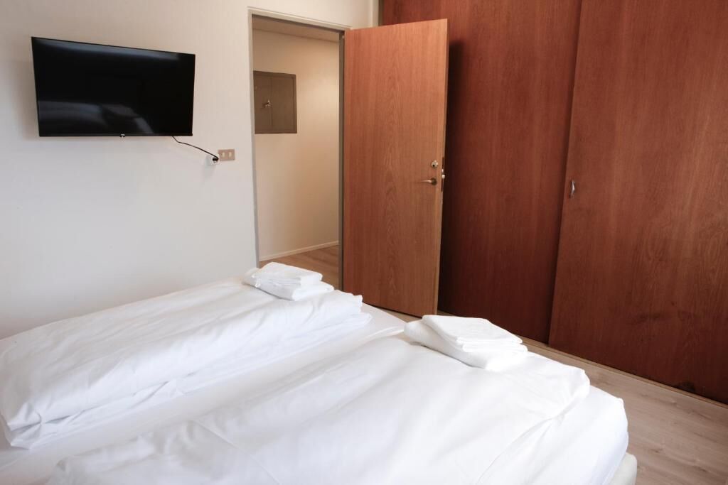 Une chambre à coucher avec un lit, un téléviseur fixé au mur et une armoire en bois.