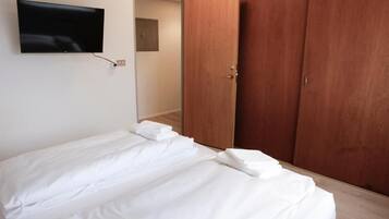 Une chambre à coucher avec un lit, un téléviseur fixé au mur et une armoire en bois.