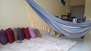 Eine Hängematte in einem Zimmer mit einem flauschigen Teppich, Kissen und einer Flagge an der Wand.