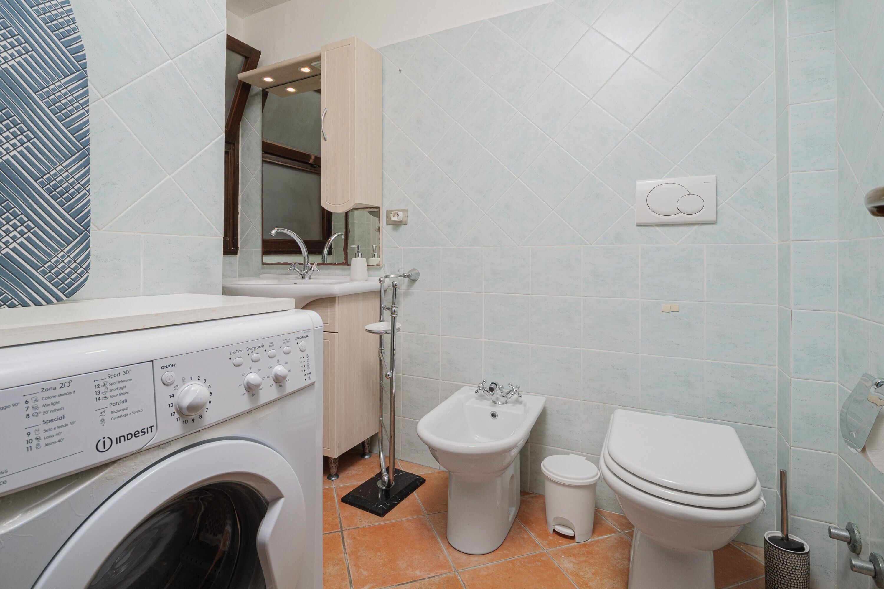 Un baño pequeño con lavadora, bidé, inodoro y espejo.