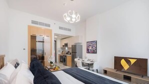 A modern hotel room with a bed, a desk, a kitchenette, and a bathroom. - Vogue | Skyz by Danube near Dubai Miracle Garden (Dubai)