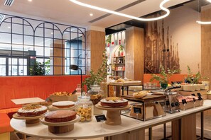 Un espace buffet proposant une variété de plats, notamment des gâteaux et des pâtisseries, présentés sur un comptoir au design intérieur moderne.