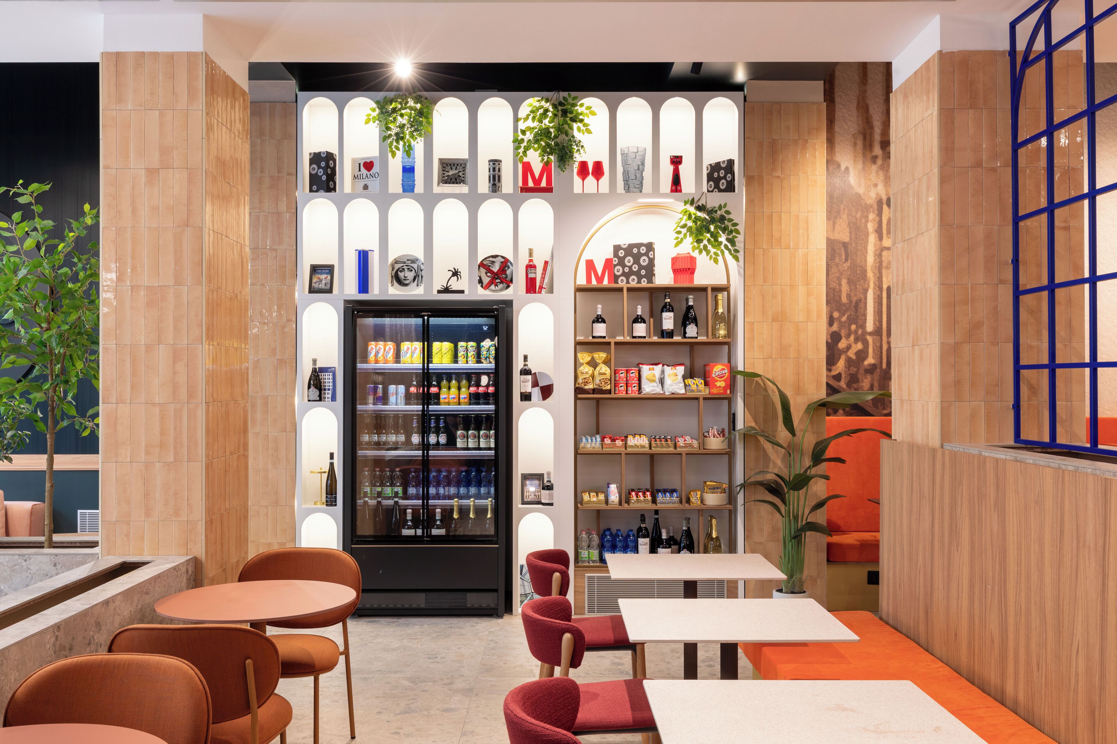 Un interior moderno con una zona de bar, asientos y una exhibición de diferentes bebidas.