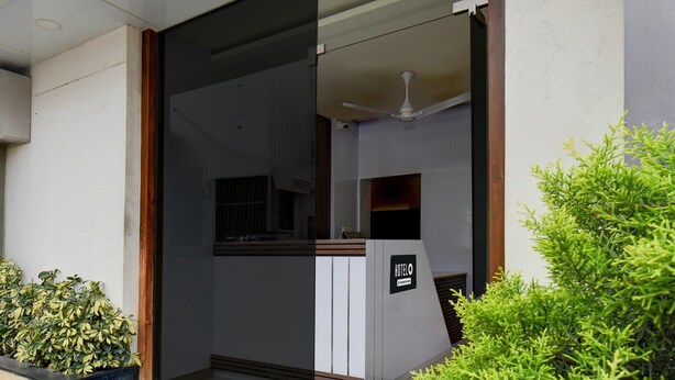 Ein Hotel-Rezeptionsbereich mit modernem Design, inklusive einer Rezeption, einem Deckenventilator und einem Schild mit dem Hotelnamen.