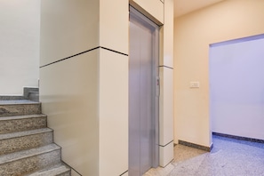 A modern interior with a staircase, a door, and a wall with a light switch.