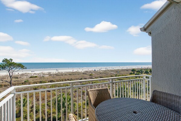 Ein Balkon mit Korbmöbeln mit Blick auf einen Strand.
