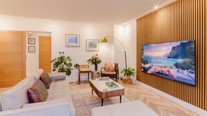 Una sala moderna con sofá, mesa de centro y televisor montado en una pared de madera.