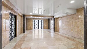 A spacious lobby with marble flooring, a glass door entrance, and a ceiling with recessed lighting. - HB apartments Jikia Residence (Tbilisi)