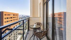 A balcony with a glass table and two wicker chairs, overlooking a cityscape with modern buildings. - HB apartments Jikia Residence (Tbilisi)