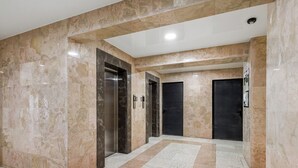 A hallway with marble flooring, two elevators, and dark doors. - HB apartments Jikia Residence (Tbilisi)