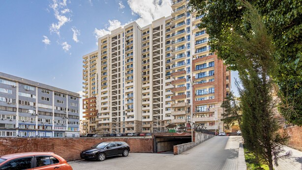 A multi-story residential building with balconies, a parking area, and a tree-lined pathway. - HB apartments Jikia Residence (Tbilisi)