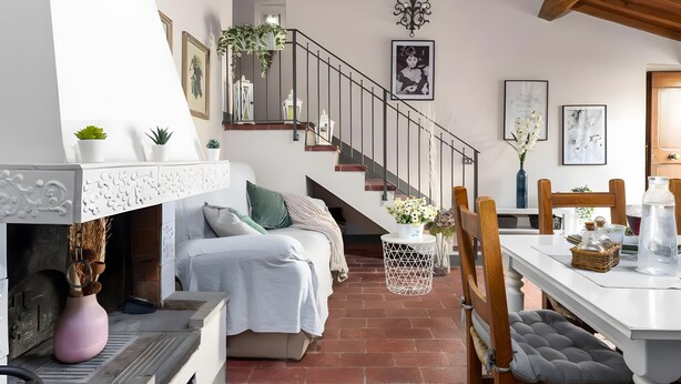 A cozy room with a fireplace, a bed, a dining table, and a staircase. - Apartment with Garden and Jacuzzi in Mugello (Barberino di Mugello)