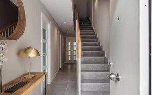 Ein Flur mit einer Treppe, einem Holzkonsolentisch und einer Lampe sowie einer Tür.