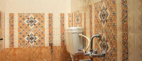 Un baño con inodoro, ducha y azulejos decorativos.