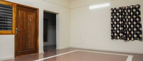A room with a wooden door, a patterned curtain, and a tiled floor.
