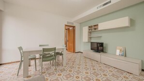 A room with a dining table, chairs, a TV, and a cabinet. - Vittoria's Flat - 15 min da Venezia (Mestre)