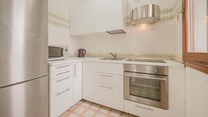 A compact kitchen with white cabinets, a stainless steel refrigerator, a microwave, and a double oven. - Vittoria's Flat - 15 min da Venezia (Mestre)