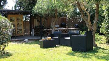 An outdoor patio with a dining table, chairs, and a barbecue grill.
