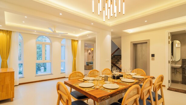 Un comedor con una mesa de madera dispuesta para cuatro personas, rodeada de sillas de mimbre con cojines azules.